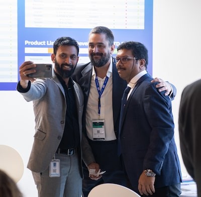 Three males in suits taking a photo with a mobile phone